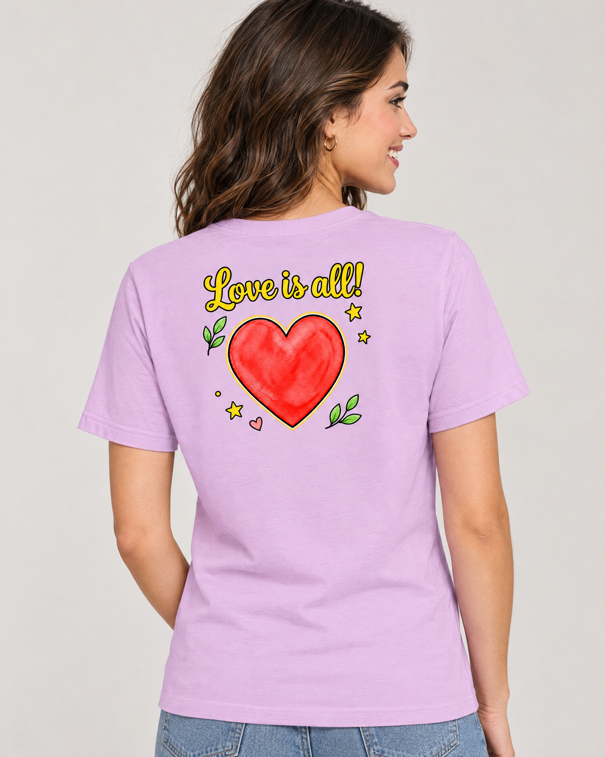 Back view of a woman wearing the Love is All! adult tee in lilac with the large Love is all! heart print on the back